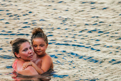 Portrait of mother and daughter in water at shore