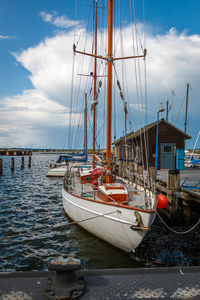 Sailboats moored in sea against sky