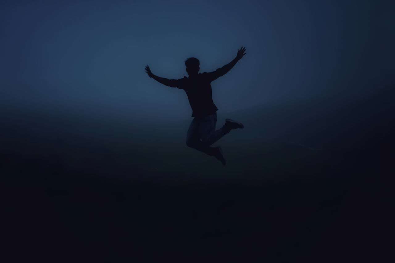 SILHOUETTE MAN WITH ARMS RAISED IN SEA