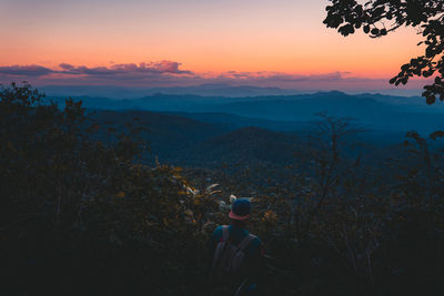 Rear view of man looking at mountains during sunset