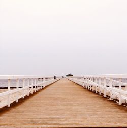 Footbridge over sea against clear sky