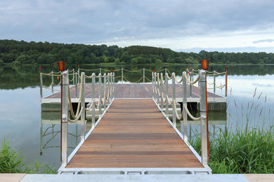 Empty wooden pier on lake against sky