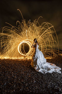 Rear view of woman standing by illuminated wire wool at night