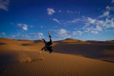 Man on sand dune in desert against sky