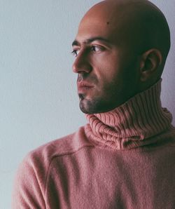 Young man wearing turtleneck sweater against wall