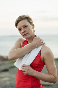 Portrait of sporty woman wiping sweat with towel outdoors