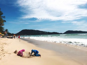 People at beach against sky