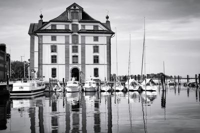 Sailboats moored in harbor against buildings in city