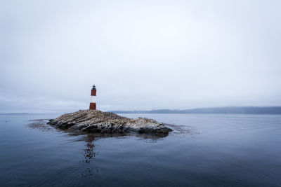 Lighthouse by sea against sky
