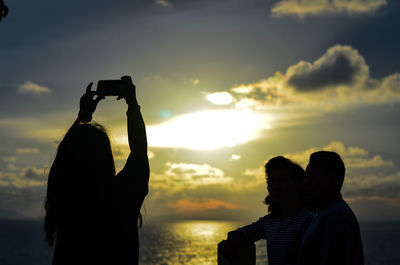 Rear view of silhouette couple against sea during sunset