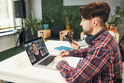 Young woman using laptop while sitting on table
