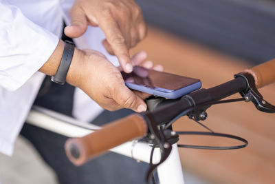 Close-up of man using smart phone while sitting on bicycle