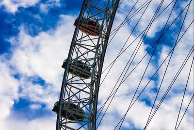 Low angle view of electricity pylon against cloudy sky