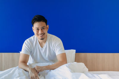 Portrait of young man sitting on bed