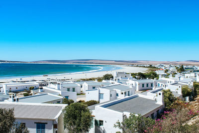 High angle view of buildings and sea against blue sky