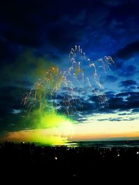 Firework display over sea against sky at night