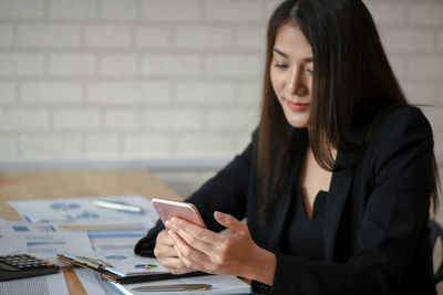 Young woman using smart phone on table