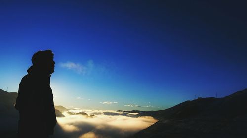 Silhouette man on mountain against sky at sunset