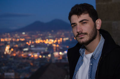 Portrait of handsome man against illuminated cityscape