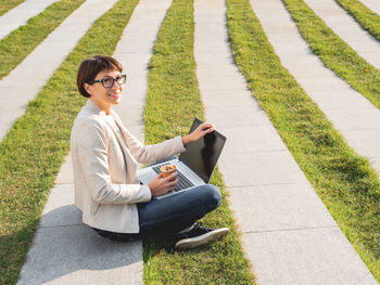 Business woman in park with laptop, cup of coffee. casual clothes, urban lifestyle of millennials.