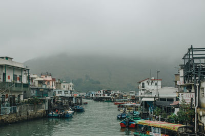 Boats moored on sea by city against sky