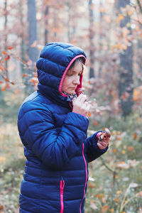 Woman wearing hood while standing in forest