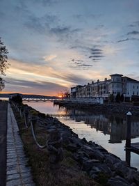 Scenic view of sea by buildings against sky during sunset