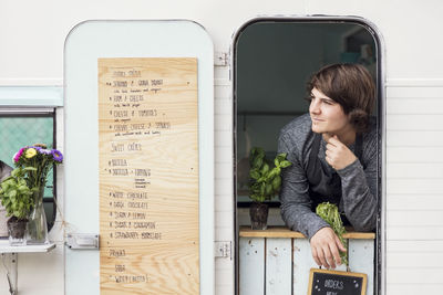 Thoughtful male owner looking out through food truck window