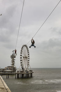 Ferris wheel by sea against sky