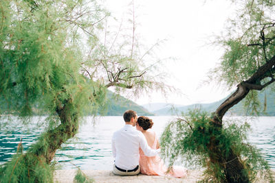 Rear view of couple sitting on water at park