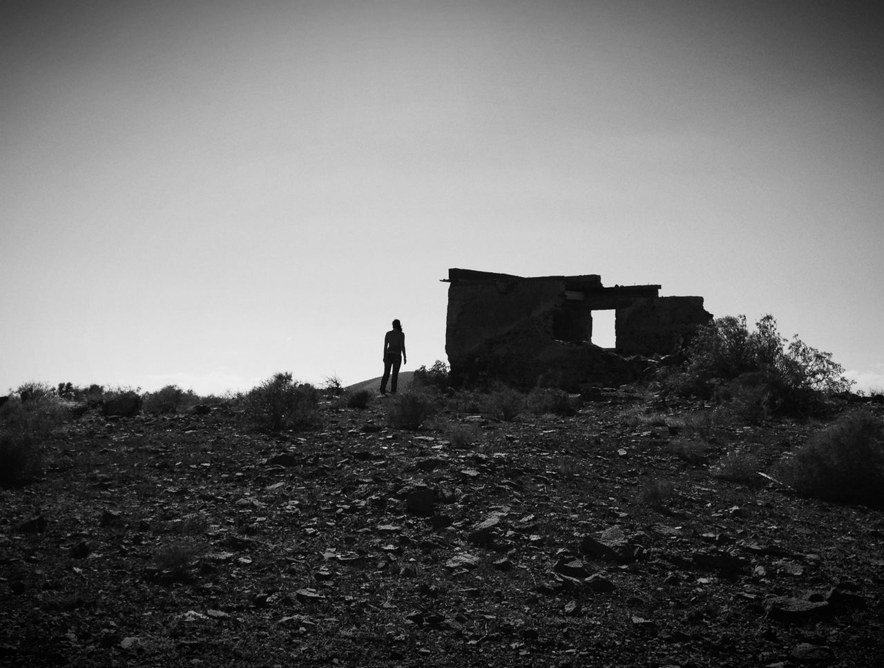 architecture, built structure, building exterior, clear sky, copy space, landscape, sky, house, hill, nature, field, tranquility, day, outdoors, old ruin, men, tranquil scene, rock - object