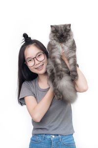 Portrait of smiling young woman with cat against white background