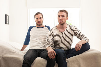 Portrait of homosexual couple sitting on bed at home