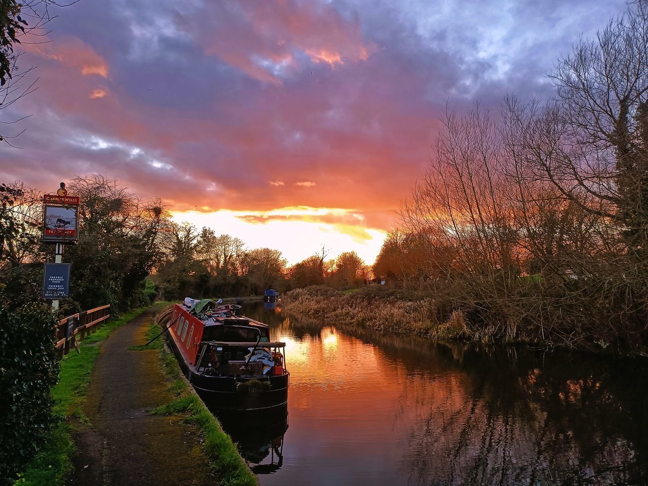 reflection, water, sky, evening, cloud, river, sunset, tree, nature, dusk, nautical vessel, transportation, waterway, plant, beauty in nature, mode of transportation, scenics - nature, tranquility, no people, autumn, architecture, sunlight, environment, outdoors, landscape, travel destinations, travel, tranquil scene, vehicle, multi colored, orange color