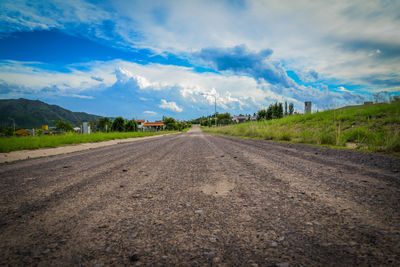 Empty road on field against cloudy sky