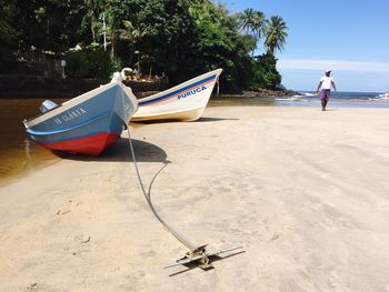 Boat moored on beach against sky