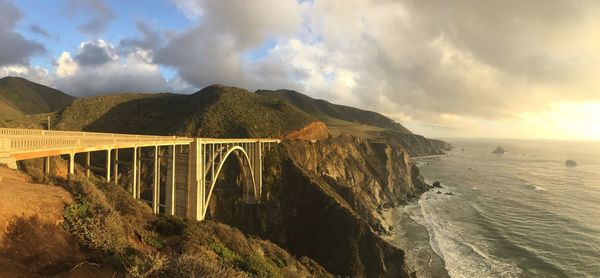 Bixby creek bridge and sea against cloudy sky 