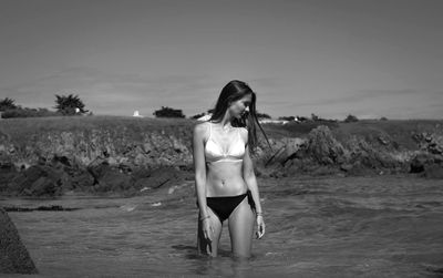 Woman standing at beach against sky