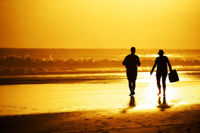 Silhouette people on beach at sunset