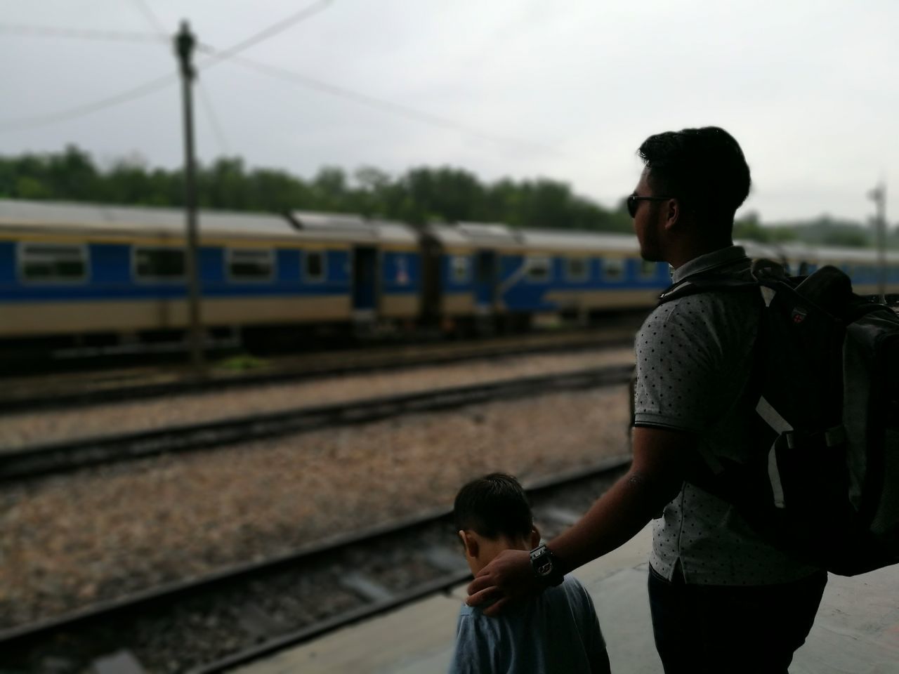 casual clothing, transportation, focus on foreground, young men, young adult, real people, passenger, mode of transport, leisure activity, train - vehicle, standing, lifestyles, public transportation, railroad station, young women, men, outdoors, people, sky, day, adult, adults only, one person, only men