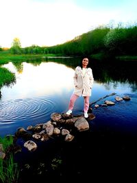 Full length of friends standing on lake against trees