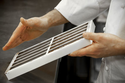 Midsection of chef holding cooking utensil in kitchen