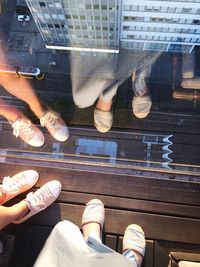 Low section of people on roof with reflection on glass