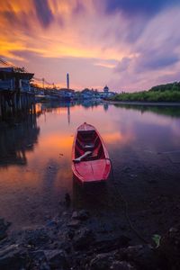 Boat moored on lake against sky during sunset