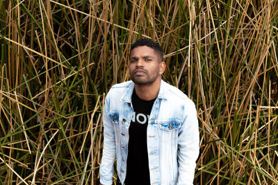 Portrait of young man standing amidst plants