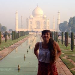 Portrait of smiling young woman standing in front of taj mahal