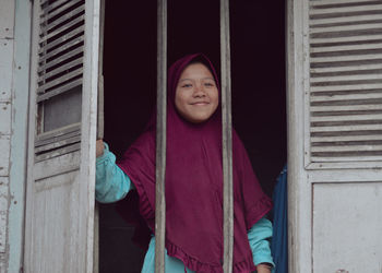 Portrait of young woman standing against wall