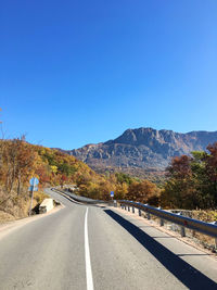 Road by mountain against clear blue sky