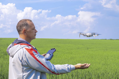 A man with a quadrocopter on the background of a field and a blue sky