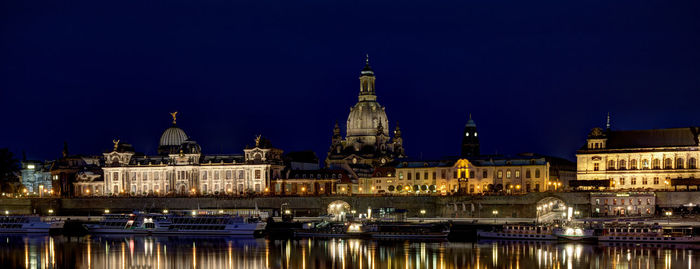 Illuminated buildings against blue sky at night